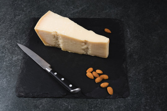 An appetizing solid cheese on a black plate on a gray stone background