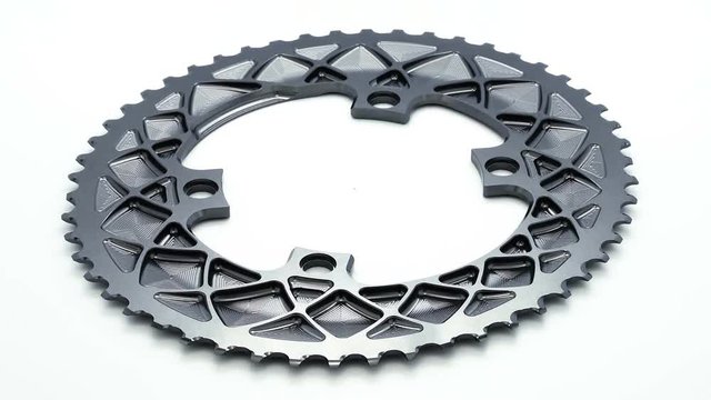 Silver oval bicycle chainring gear rotating at white background