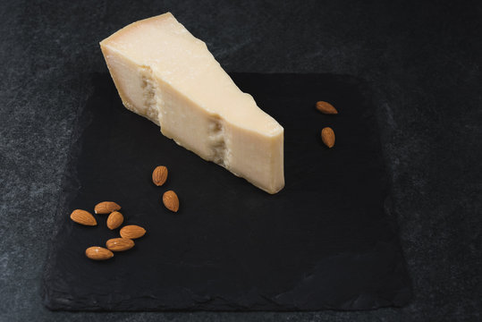An appetizing solid cheese on a black plate on a gray stone background