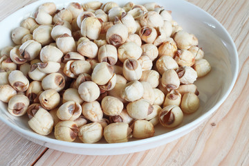 Lotus seed on white plate with background wood table.