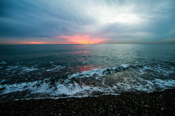 Coastal waves at sunset. Colorful sunset on a sea beach.