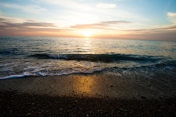 Coastal waves at sunset. Colorful sunset on a sea beach.
