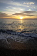 Coastal waves at sunset. Colorful sunset on a sea beach.