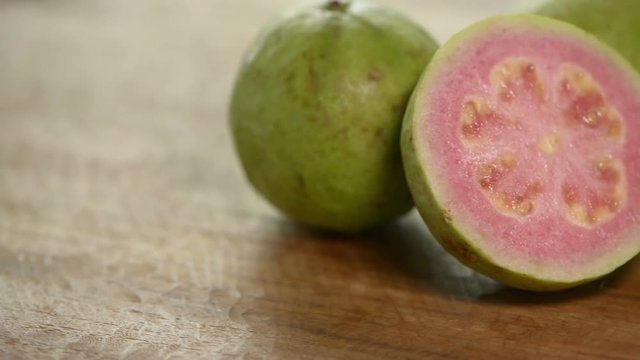 Cuted pink guava rotates on wooden table