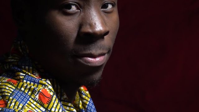 Side view as a black man from Angola puts on his neck a bright handkerchief and turns on the camera