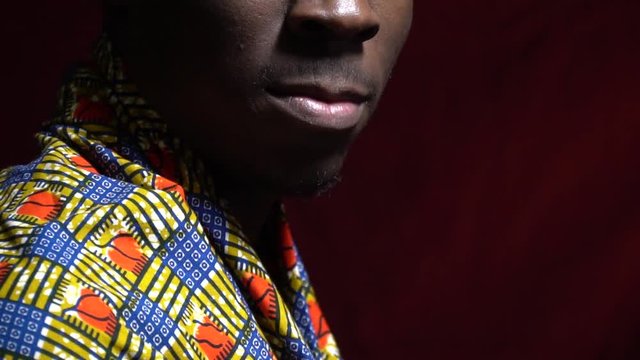 Side view as a black man in dashiki puts on his shoulders a handkerchief