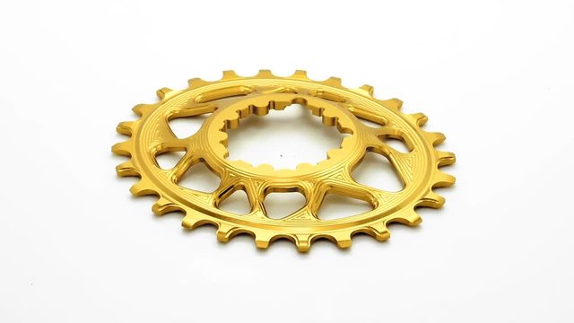  Golden oval bicycle chainring gear rotating at white background
