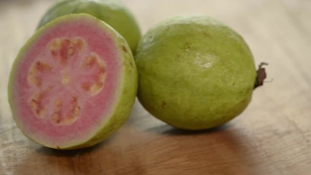 Cuted pink guava rotates on wooden table