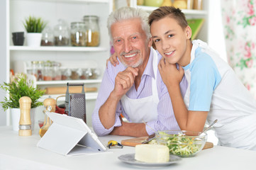 Senior man with grandson preparing dinner in kitchen