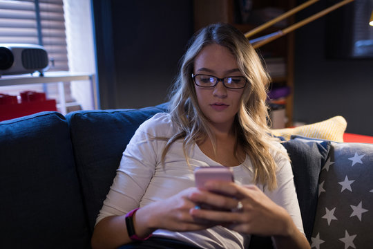 Young woman using her mobile phone on the sofa
