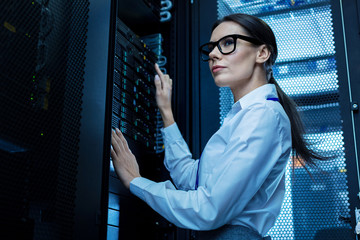 Good working day. Determined pretty woman working with server equipment and wearing glasses - obrazy, fototapety, plakaty