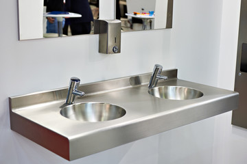 Metal sink with taps in public toilet