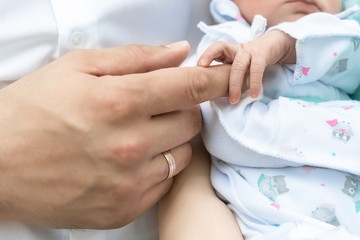 Obraz na płótnie Canvas father's hands holding his newborn son fingers