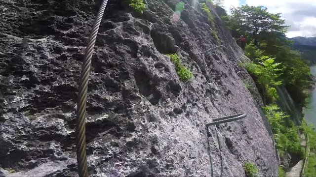 POV - a man climbs up a cliff with the help of iron handles