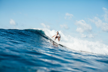 handsome sportsman surfing on ocean wave on sunny day