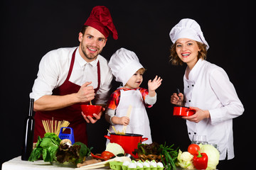 Parents with child preparing dinner. Cheerful parents teaching a boy how to cook. Concept of friendly family. Homemade food. Happy family in kitchen. Healthy food at home.