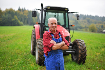 Proud farmer standing in front of his red tractor