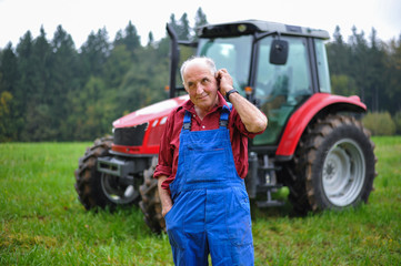 Proud farmer standing in front of his red tractor