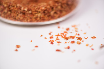 Coarsely ground chilli peppers in glass bowl isolated on white background.