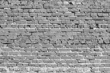 Brick wall. The bricks cracked. Masonry is uneven. Wall is covered or stained with cement mortar. Laying with alternation. Many layers. There are broken bricks. Background, backdrop or Wallpaper.
