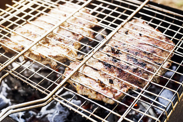 Two beef steaks on the grid are prepared on the grill outdoor - a family barbecue. Summer fresh aromatic dishes