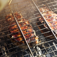 Two pork steaks on the grid are prepared on the grill outdoor. Summer family barbecue concept
