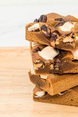 Blondie cake with marshmallow and dark chocolate on wood plate.