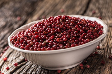 Red peppercorn in bowl on oak table