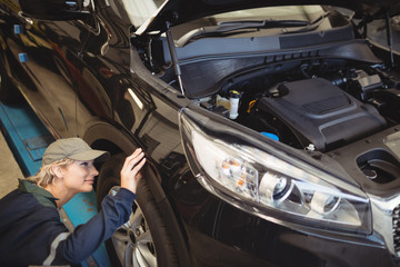 Female mechanic examining a car wheel
