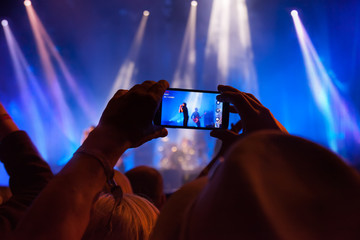Person capturing a video  on a mobile phone at a music festival.