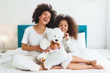Mother and daughter enjoying on the bed, happy, smiling 