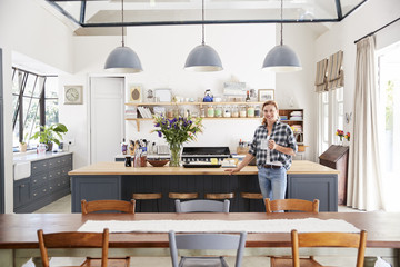Woman leaning on island in an open plan kitchen dining room