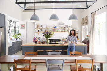 Mixed race woman in open plan kitchen looking to camera