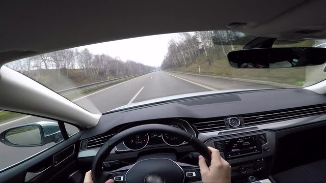 POV - a man drives a luxurious car down a highway in a countryside