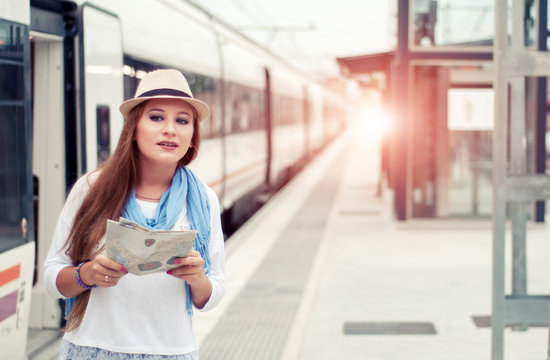 Traveler girl waiting and  boarding a train on railway platform. Travel concept.