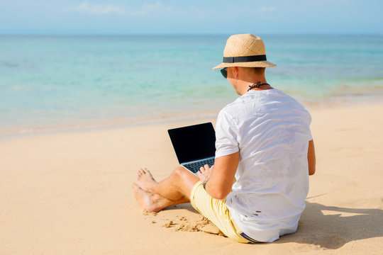 Relaxed man working with laptop on the beach