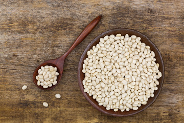 White pea beans, also called Navy bean, Pearl Haricot, Boston bean in clay bowl on wood
