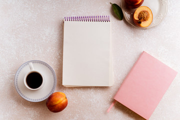 Flatlay image of female workspace with blank sketchbook, cup of coffee and fruit snacks