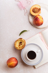 Flatlay image of female workspace with notepad, cup of coffee and fruit snacks in blush pink color setting