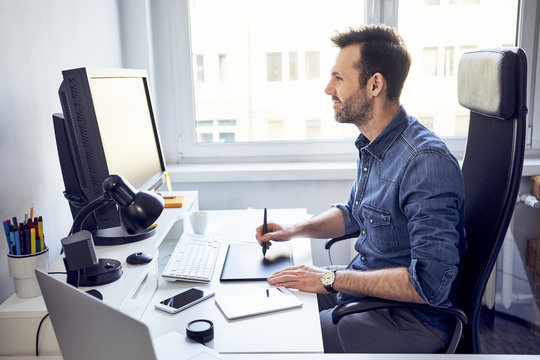 Smiling graphic designer working on computer at desk in office