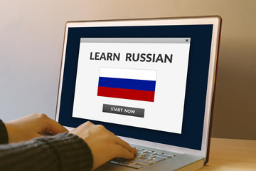 Learn Russian concept on laptop computer screen on wooden table. Hands typing on a keyboard. All screen content is designed by me. 