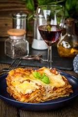 Piece of tasty hot lasagna with red wine.