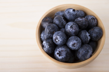 Berries of blueberry with drops of dew in a wooden bowl