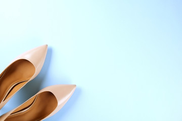 Stylish classic women's beige leather shoes with medium high heels shot from top on pale blue background. Copy space, top view, flat lay. Shoe sale / clearance ad concept.