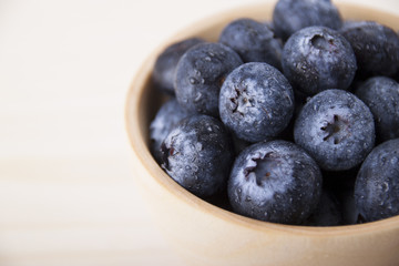 Berries of blueberry with drops of dew in a wooden bowl closeup