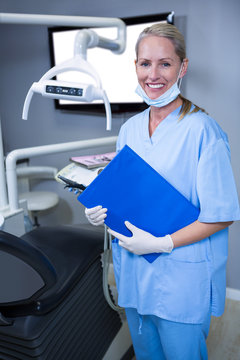 Smiling Dental Assistant In Blue Scrubs Holding A Clipboard