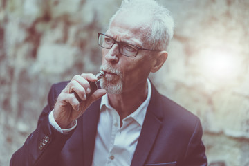 Mature man smoking electronic cigarette, light effect