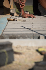 Close up view of worker laying brick on ground
