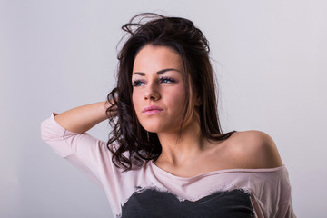 Beautiful young brunette woman posing in studio before white wall