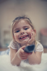 Portrait of little girl with remote controller in hand.